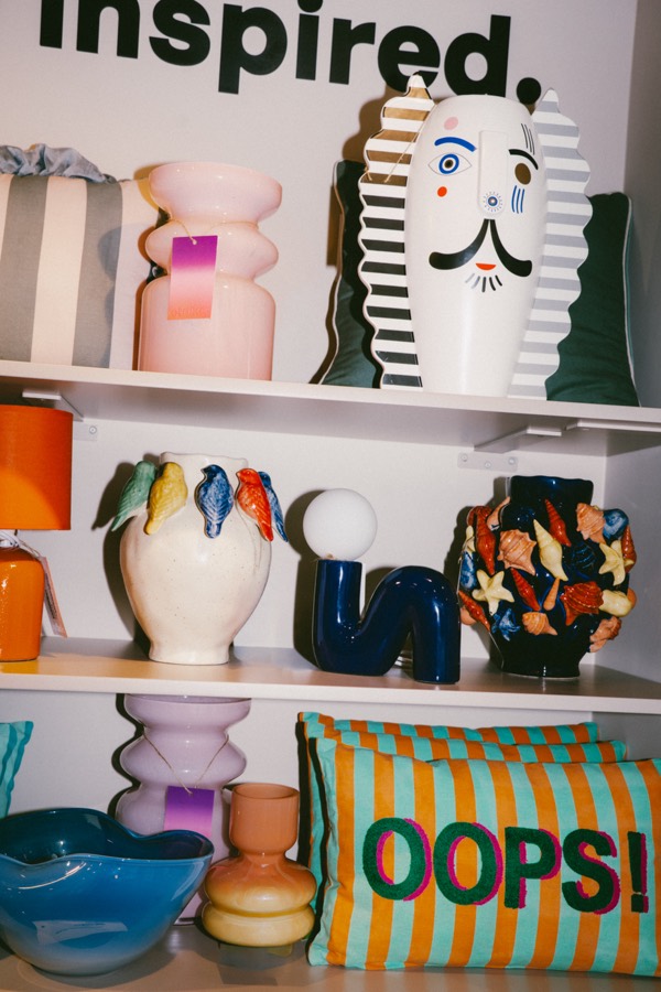 Półka z designerskimi wazonami i poduszką z napisem OOPS